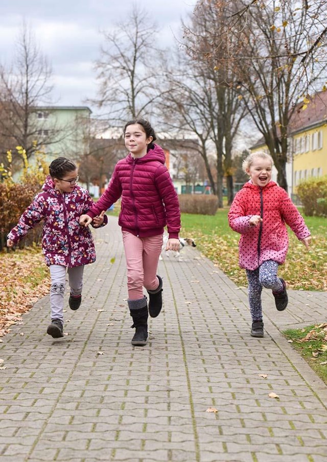 Drei kleine Mädchen rennen Hand in Hand Richtung Kamera